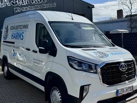 Weißer Transporter mit Beschriftung Gebäudetechnik Harms vor der Halle von 1aShirt in Emden