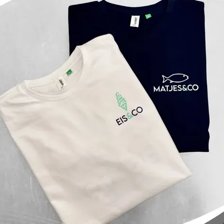 Zwei gefaltete Shirts: weiß mit Logo Eis und Co, navy mit Logo Matjes und Co